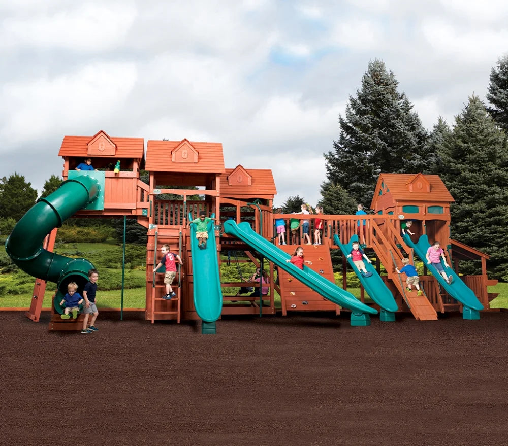 Niños jugando en un gran parque infantil de madera con toboganes y estructuras para trepar.